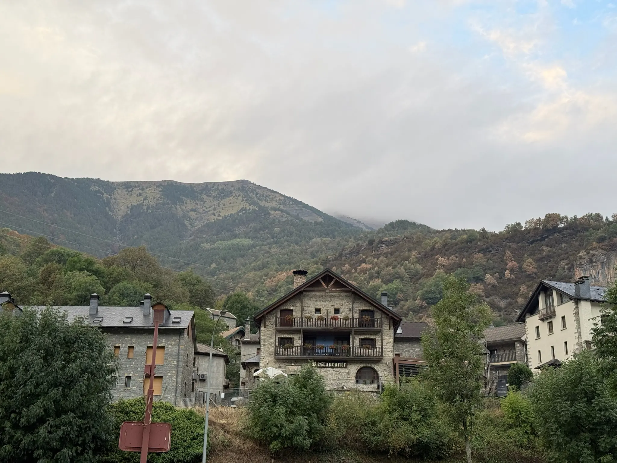 Casas de piedra con balcones de madera en Torla con restaurante y montaña boscosa al fondo. Foto propia La Maleta Inquieta, octubre 2026