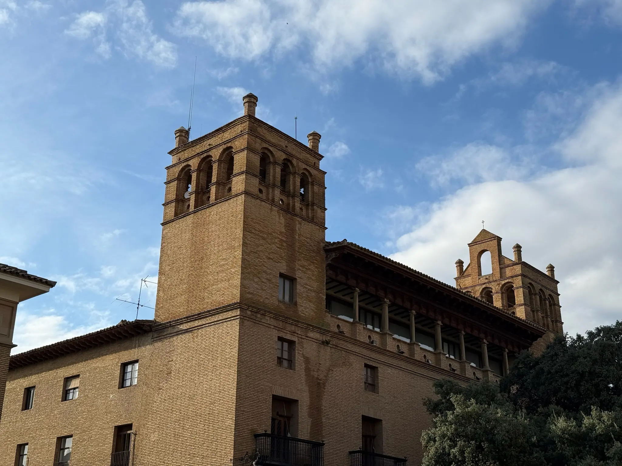 Edificio de ladrillo con torre de arcos, galería aragonesa y espadaña en el entorno de la Catedral de Huesca. Foto propia La Maleta Inquieta, octubre 2026